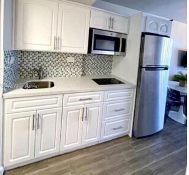 kitchen with stainless steel appliances, sink, white cabinetry, and tasteful backsplash