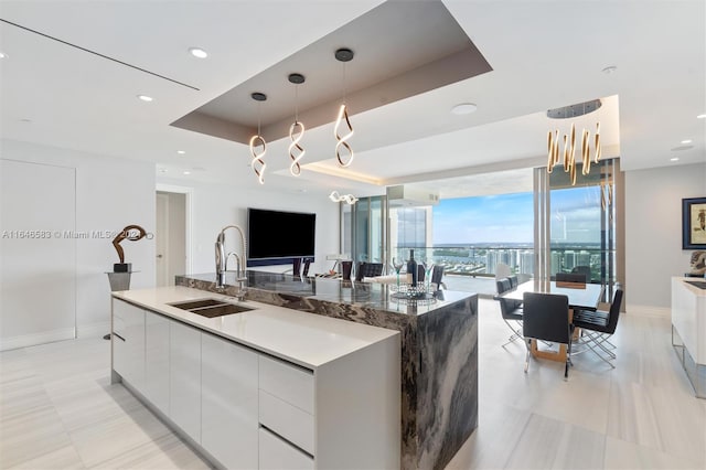 kitchen with hanging light fixtures, white cabinets, modern cabinets, a raised ceiling, and a sink