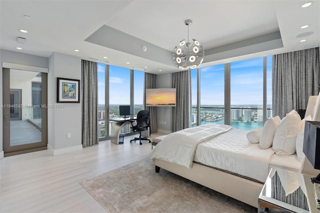 bedroom featuring baseboards, a wall of windows, recessed lighting, wood finished floors, and a raised ceiling