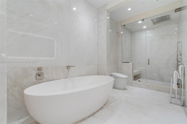 bathroom featuring toilet, marble finish floor, a marble finish shower, tile walls, and a freestanding bath