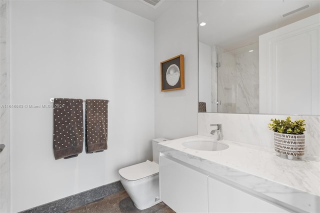 full bath featuring a marble finish shower, toilet, and vanity