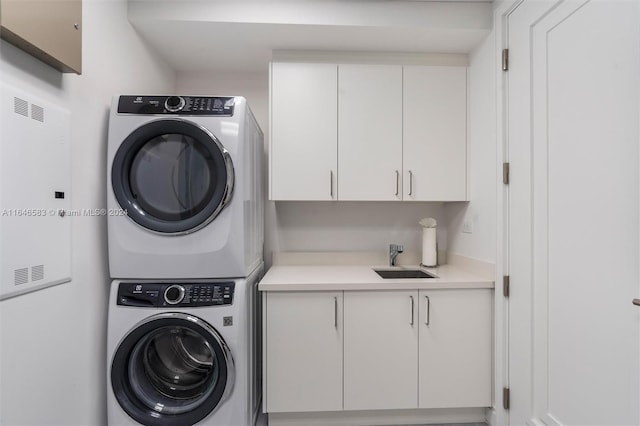 clothes washing area featuring cabinet space, stacked washing maching and dryer, and a sink