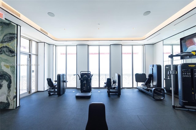 workout area with a wall of windows and a tray ceiling