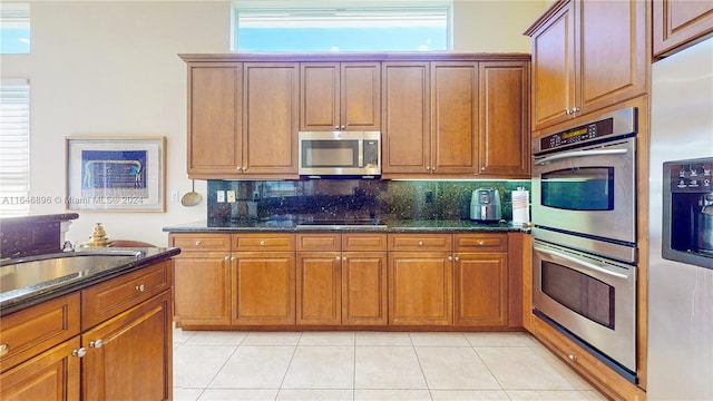 kitchen featuring tasteful backsplash, a wealth of natural light, stainless steel appliances, and dark stone counters