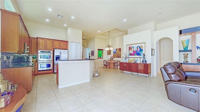 kitchen with hanging light fixtures, stainless steel appliances, a center island, an inviting chandelier, and decorative backsplash