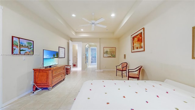 bedroom with a raised ceiling, light tile patterned floors, and ceiling fan