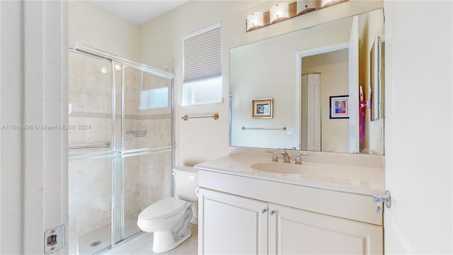 bathroom with vanity, toilet, a shower with shower door, and tile patterned floors