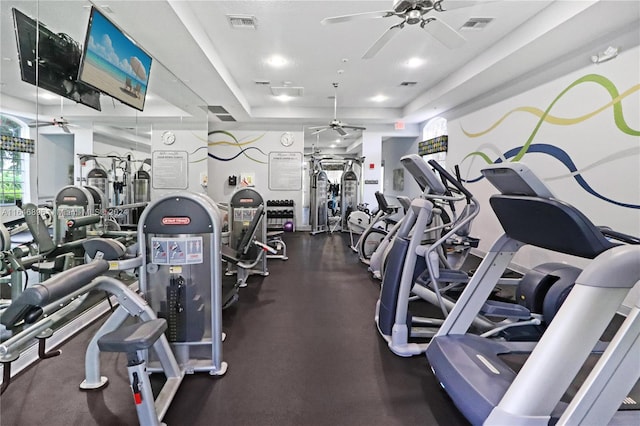 exercise room featuring a tray ceiling and ceiling fan