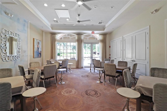 dining area with a raised ceiling, a skylight, dark colored carpet, and ceiling fan