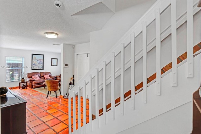 stairs featuring a textured ceiling and tile patterned flooring