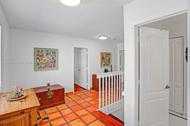 hall featuring a textured ceiling and light tile patterned floors