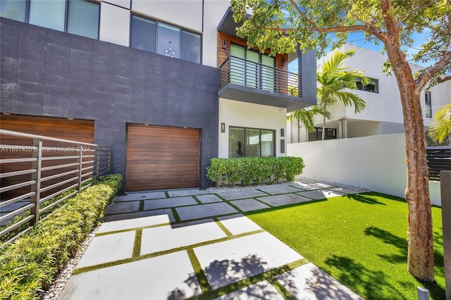 back of house with a balcony, a garage, and a yard