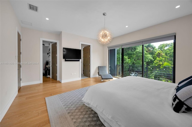 bedroom featuring light hardwood / wood-style flooring, a walk in closet, access to exterior, and a closet