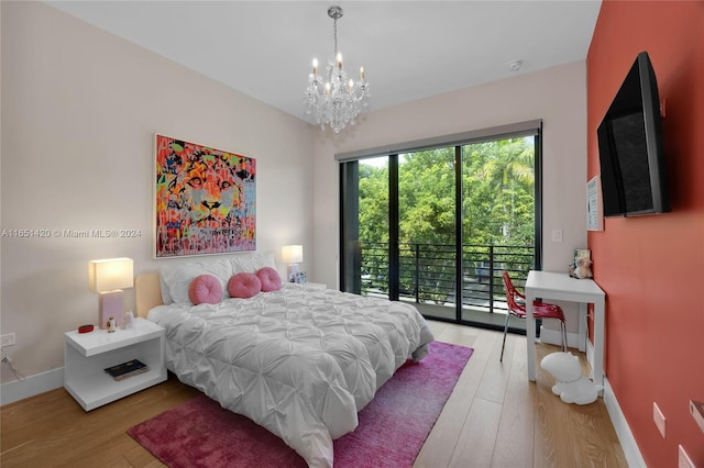 bedroom featuring light wood-type flooring, access to outside, and an inviting chandelier