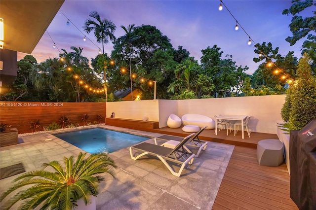 pool at dusk featuring a wooden deck