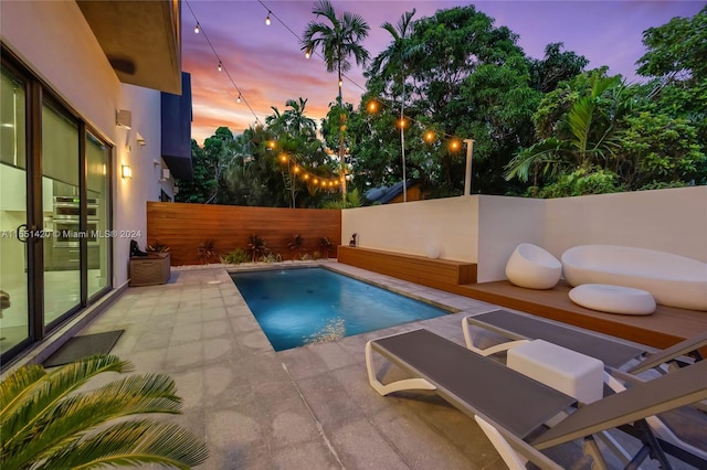 pool at dusk with a patio area