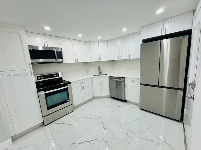 kitchen featuring stainless steel appliances, sink, decorative backsplash, and white cabinetry