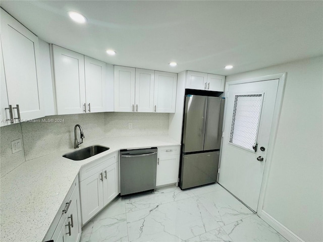 kitchen with sink, light stone countertops, appliances with stainless steel finishes, and white cabinets