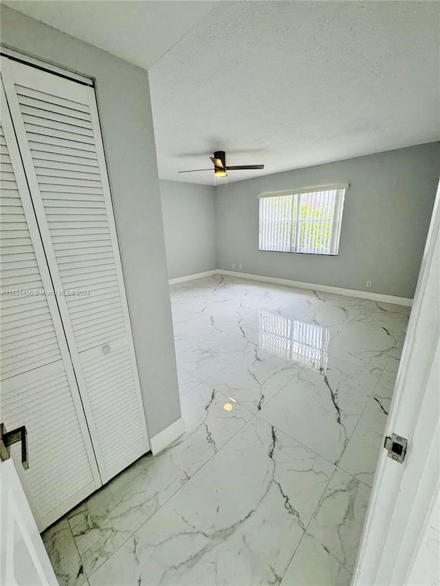 unfurnished room featuring ceiling fan and a textured ceiling