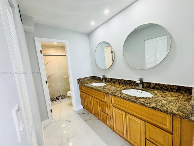 bathroom featuring a shower with door, vanity, and toilet