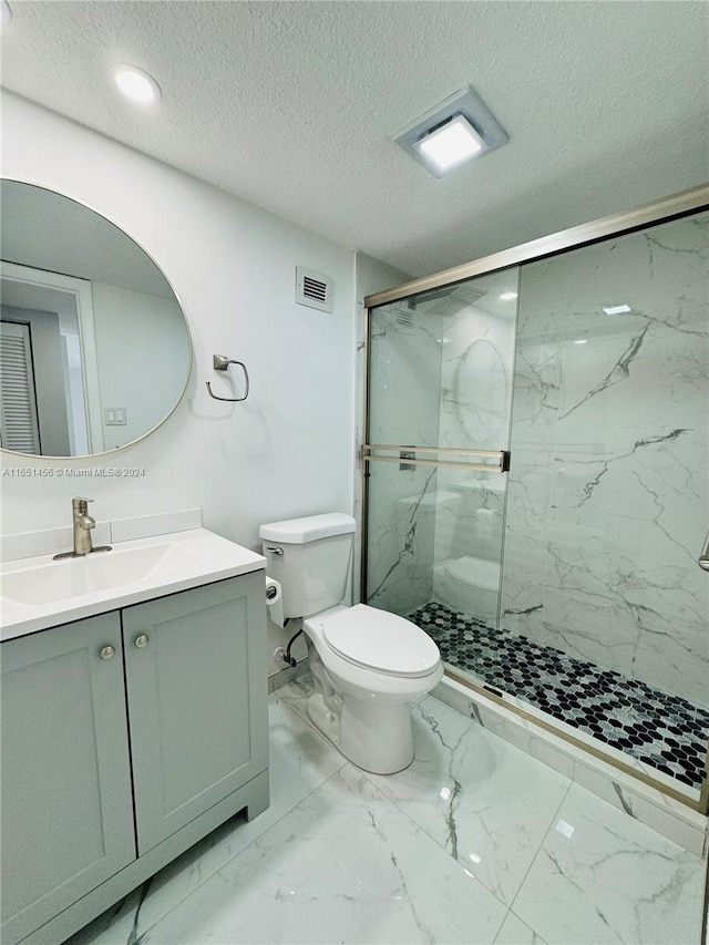 bathroom featuring vanity, toilet, an enclosed shower, and a textured ceiling