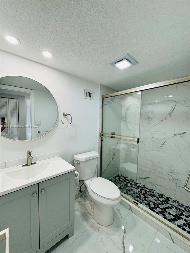 bathroom with vanity, toilet, a textured ceiling, and a shower with shower door