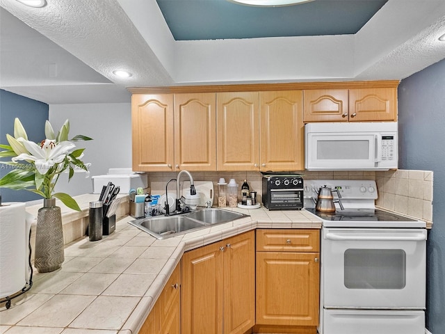 kitchen featuring tile counters, sink, white appliances, and decorative backsplash