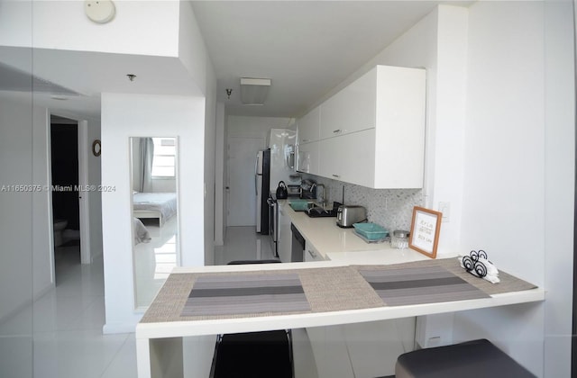 100 Lincoln Rd Unit 1605, Miami Beach, FL 33139 - kitchen featuring backsplash, white cabinets, light tile patterned floors, freestanding refrigerator, and stainless steel dishwasher