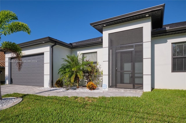 entrance to property featuring a yard and a garage