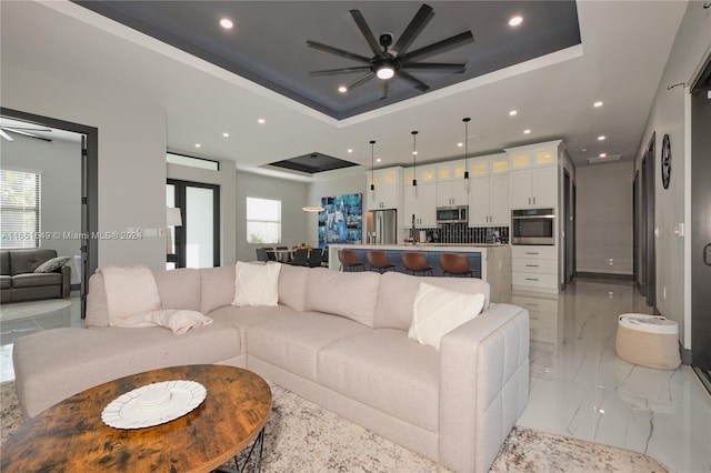 living room featuring a raised ceiling and ceiling fan