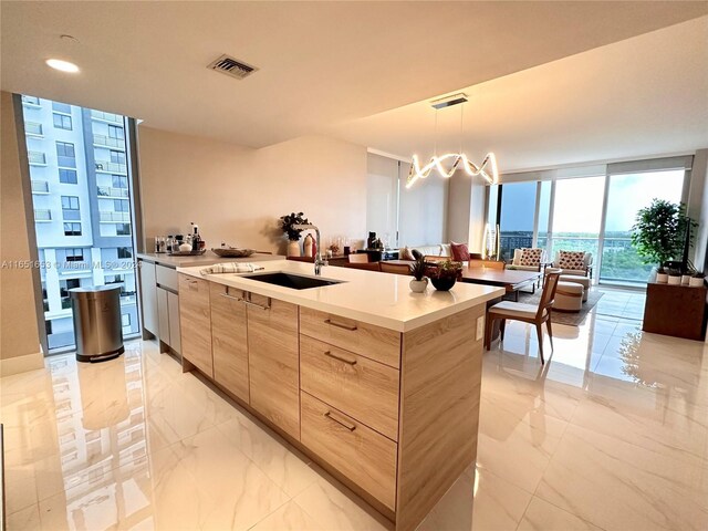 kitchen featuring decorative light fixtures, a notable chandelier, sink, light brown cabinets, and floor to ceiling windows