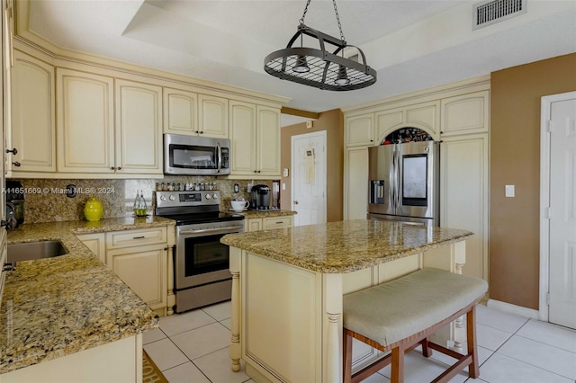 kitchen featuring cream cabinetry, appliances with stainless steel finishes, a center island, and a breakfast bar