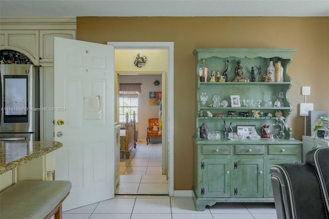 interior space with light stone counters, light tile patterned floors, and green cabinets