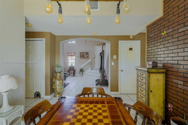 dining space with brick wall and light tile patterned floors