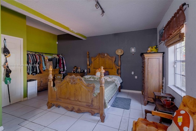 tiled bedroom with a textured ceiling and track lighting