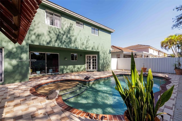 rear view of house featuring a fenced in pool, french doors, and a patio area