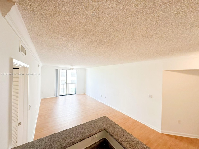 unfurnished room featuring ceiling fan, a textured ceiling, and light hardwood / wood-style flooring