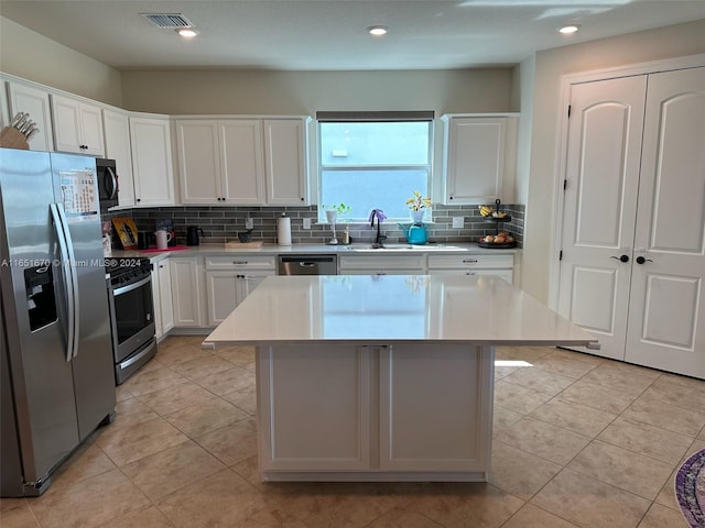 kitchen with a kitchen island, tasteful backsplash, stainless steel appliances, sink, and white cabinetry