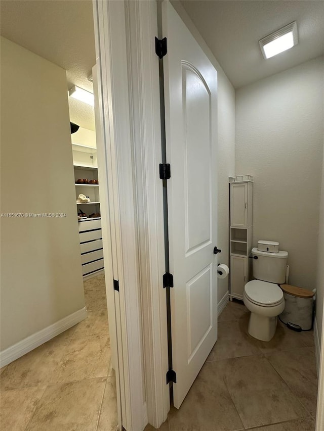 bathroom with a textured ceiling, toilet, and tile patterned floors