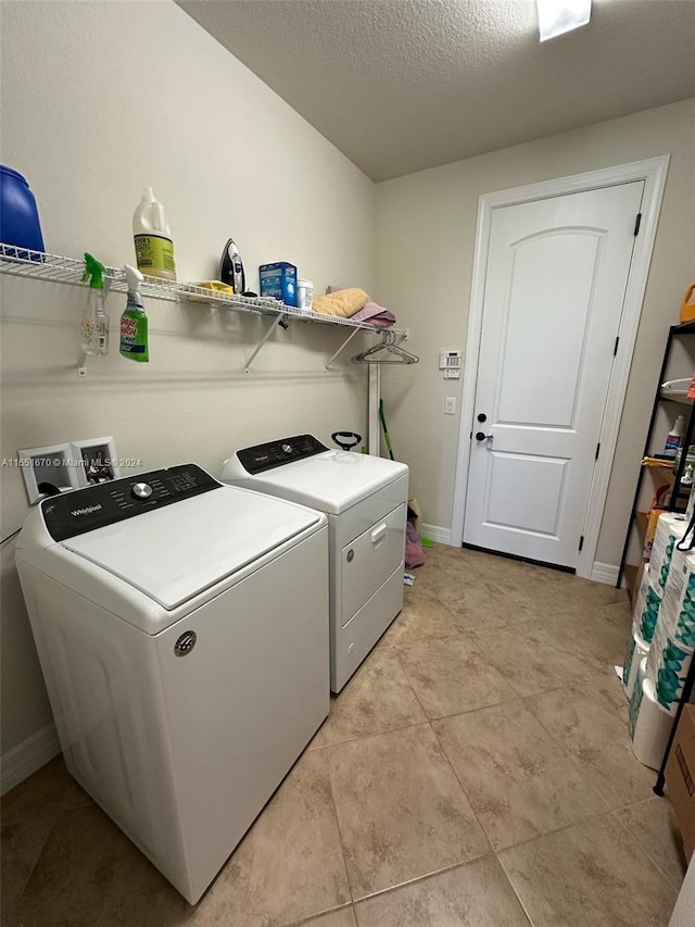 clothes washing area with a textured ceiling, washing machine and dryer, and light tile patterned floors