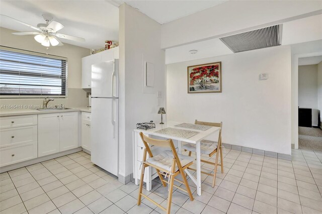 kitchen featuring white fridge, light tile patterned floors, sink, ceiling fan, and white cabinets