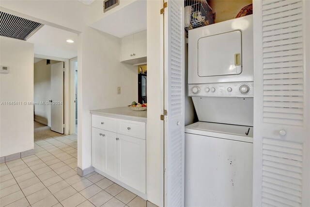 laundry area with light tile patterned flooring and stacked washer / dryer