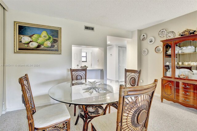 dining space featuring a textured ceiling and light colored carpet