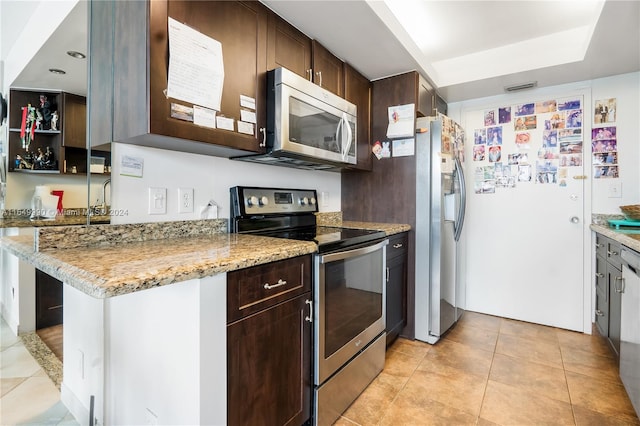 kitchen featuring light tile patterned floors, stainless steel appliances, light stone countertops, and dark brown cabinetry