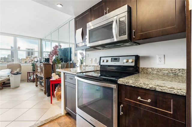 kitchen featuring light tile patterned floors, appliances with stainless steel finishes, light stone counters, and dark brown cabinets