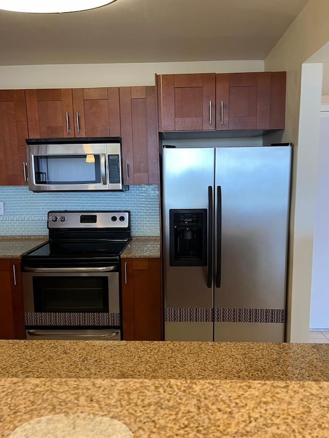 kitchen featuring appliances with stainless steel finishes, light stone countertops, and tasteful backsplash