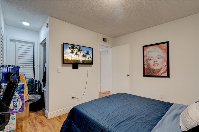 bedroom featuring a textured ceiling and light hardwood / wood-style flooring