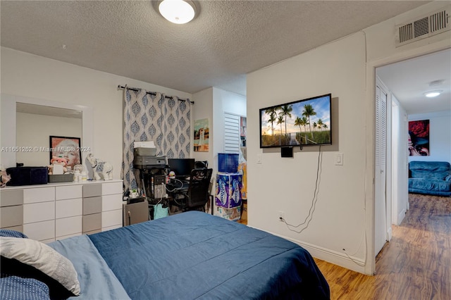 bedroom with a textured ceiling and light hardwood / wood-style flooring