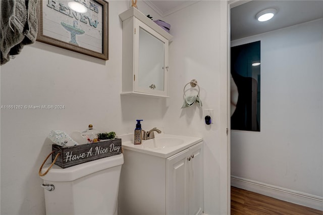 bathroom with toilet, hardwood / wood-style flooring, ornamental molding, and vanity