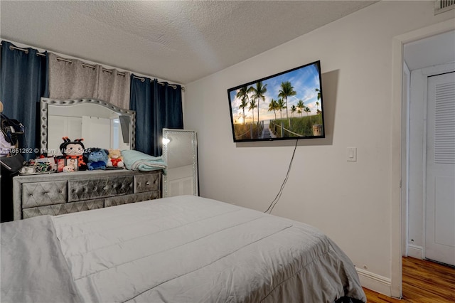 bedroom with wood-type flooring and a textured ceiling